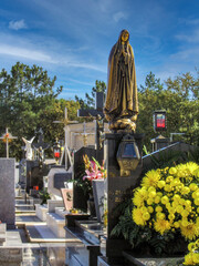 Famalicao, Portugal. Typical Portuguese Catholic cemetery with marble headstones, flowers, Jesus Christ crucifixes and statues of Our Lady of Fatima