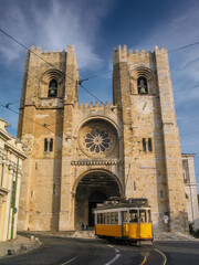 Lisbon, Portugal. An iconic yellow tram passes in front of the Lisbon Cathedral or Se de Lisboa aka Santa Maria Maior Church in the Alfama District.