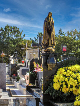 Famalicao, Portugal. Typical Portuguese Catholic cemetery with marble headstones, flowers, Jesus Christ crucifixes and statues of Our Lady of Fatima