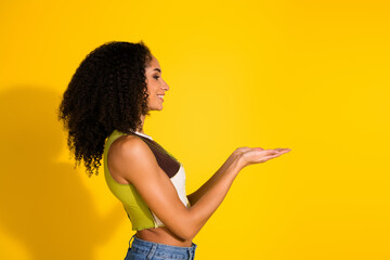 Side view of a cheerful woman showing a gesture on a bright yellow background
