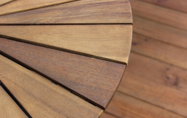  Part of a round wooden garden table under a blurred wooden terrace floor. Outdoor and garden furniture stock image 
