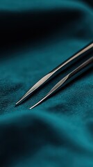 Two shiny needles lie on top of teal colored fabric