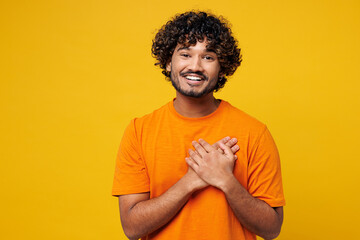 Young smiling thankful cheerful happy Indian man he wearing orange t-shirt casual clothes put...