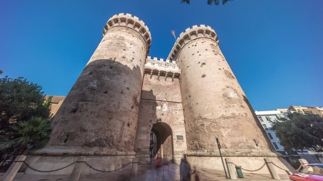 Towers of Quart timelapse hyperlapse in Valencia, Spain. Historical medieval gate, part of the ancient city walls. Popular landmark with a rich cultural heritage. Blue sky and street traffic scene.