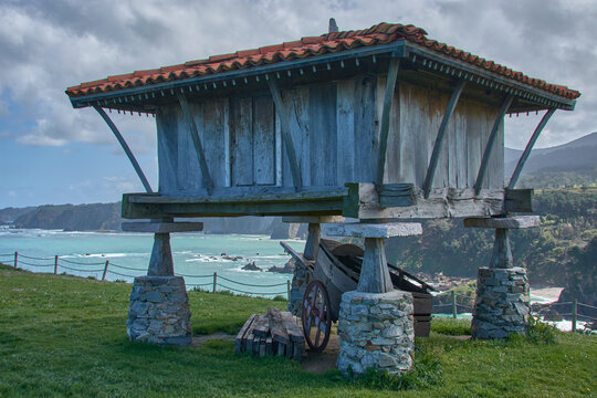 Asturian horreo with cart and ocean backdrop from Senda de Cadavedo in Cabo de Busto, Asturias, Spain.