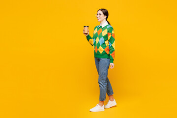 Fototapeta premium Full body young woman wear glasses green sweater casual clothes hold takeaway delivery craft paper brown cup coffee to go isolated on plain orange yellow background studio portrait. Lifestyle concept.