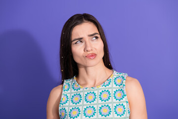 Fototapeta premium Young woman with a skeptical expression against a vibrant purple background wearing a stylish summer outfit