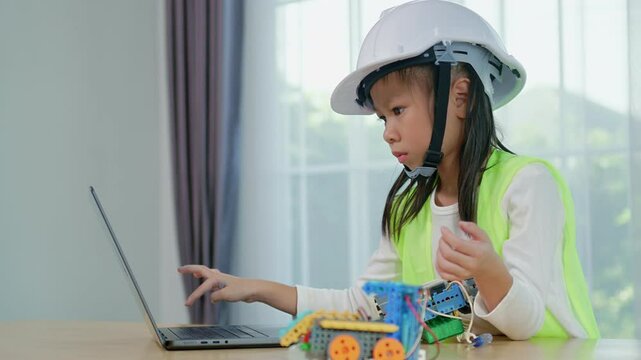 Kid playing with construction blocks on table and hands typing on laptop computer, child playing and building with colorful plastic bricks. Early learning and development.
