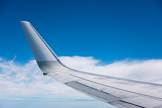 airplane wing against clouds and blue sky