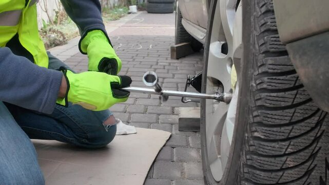 A guy changes tire on street to summer tire in nature