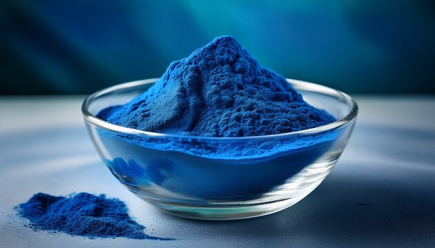 close up of blue spirulina powder in a clear glass bowl