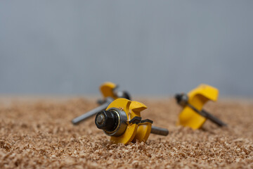 Yellow bits for router saw on a sawdust covered surface. Tools for woodworking and carpentry...