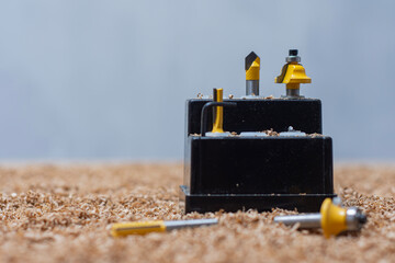 Yellow bits for router saw on a sawdust covered surface. Tools for woodworking and carpentry...