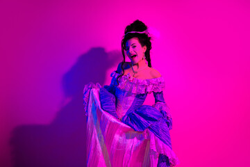 Fototapeta premium Vibrant young woman in a historical costume adorned with vivid colors and elegant details under neon lighting
