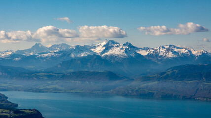 Snow-capped mountains overlook a serene lake under a clear blue sky in the morning light