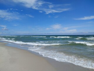 Tranquil Summer Day at Baltic Beach with Gentle Waves Embracing Sandy Shoreline Under Expansive Blue Sky