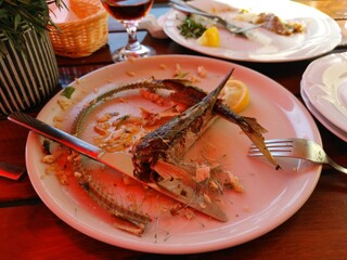 Closeup of Eaten Red Scorpion Fish with Fork on White Plate in Upscale Restaurant Setting