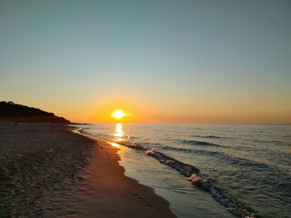 Majestic Coastal Sunset with Sun Touching Horizon Where Sandy Beach Meets Baltic Sea Creating Perfect Golden Pathway