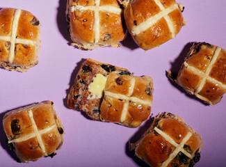 Top view of some hot cross buns with a purple background.