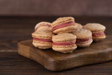 Vegan homemade macaroons with raspberry cream on shea butter on a brown wooden table. Sugar, lactose and gluten free.