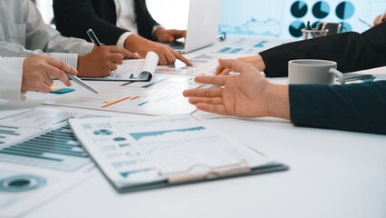 A diverse group of professionals engages in a dynamic meeting, analyzing charts and data on a modern office table while discussing business strategies and insights. SACTR