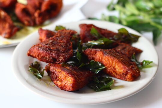 Vietnam pearl spot fish marinated with aromatic spices and fried to golden perfection, garnished with fresh curry leaves