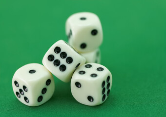 Hand dropping four white dice with black dots onto a green surfa