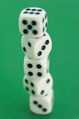 Stack of white dice balancing on a green background during a gam