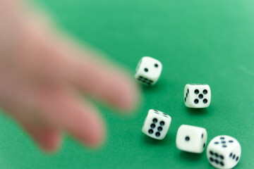 Playing dice on a green table with a hand reaching for the rolli