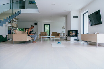 African American man in glasses sitting at a table in a modern living room, using a laptop for business video chat, conversation with friends and entertainment.