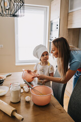 Daughter and mother making pizza together for dinner at the kitchen