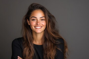 Fototapeta premium Smiling woman with long hair stands confidently against a neutral background