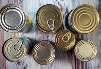 There are closed metal cans on the table.   Canning jars contain food prepared for consumption. Close-up. Top view.