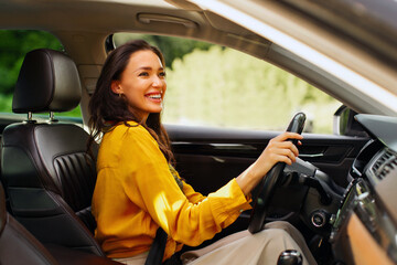 Happy woman holding hands on steering wheel, look rearview mirror and parking, enjoying car ride...