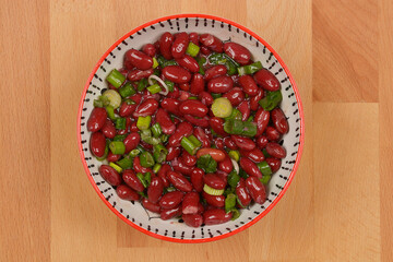 Red kidney bean saladRed kidney bean salad with spring onions in a decorative bowl, shot from above on a wooden surface