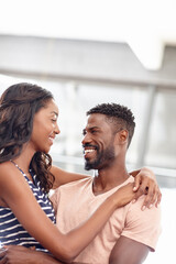 Obraz premium Black couple, smile and romantic hug in home, healthy relationship and love in living room. Happy people, bonding and trust commitment in marriage, embrace affection and eye contact for connection