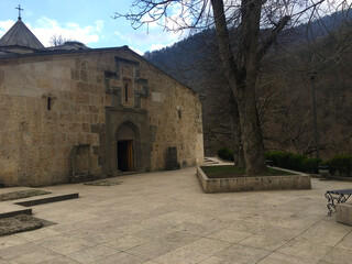 Chapel facade with carved cross and gated entrance in quiet mountain setting Stone building sits in tranquil courtyard as distant peaks fade into soft skyline