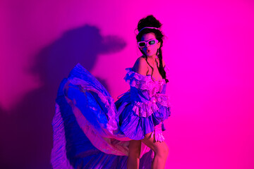 Elegant woman in historic styled dress posing in vibrant ultraviolet lighting