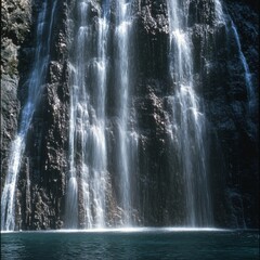 Serene waterfall cascading over rocky cliff into blue pool