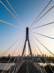 modern metal cable bridge over Vistula river at sunset, contemporary geometric architecture, cable-stayed bridge at city skyline, symmetry and architectural urban contrast, Warsaw