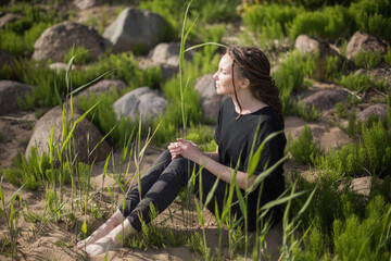 Young Woman Sitting on a Sandy Beach, Gazing into the Distance