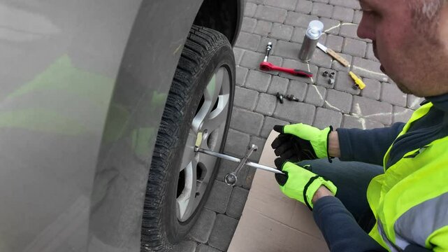 A guy changes tire on street to summer tire in nature