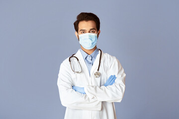Confident Indian doctor wearing medical mask and rubber gloves on lilac background
