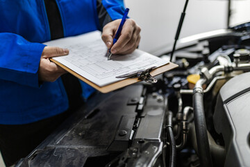 Mechanic conducting vehicle inspection with clipboard and checklist in automotive workshop
