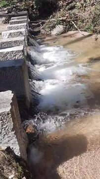 agua pasando entre las piedras de una pasarela peatonal de una riera de Les Guilleries