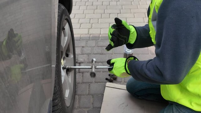 A guy changes tire on street to summer tire in nature