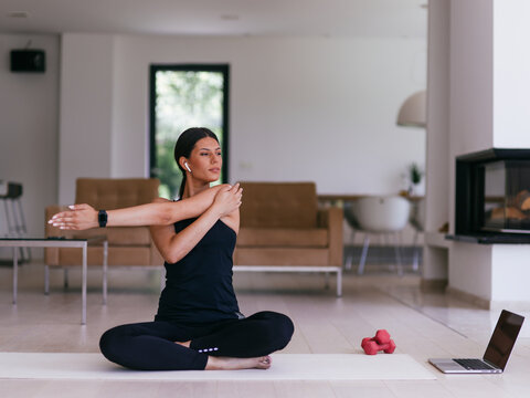 Young Beautiful Female Exercising, Stretching and Practising Yoga with Trainer via Video Call Conference in Bright Sunny House. Healthy Lifestyle, Wellbeing and Mindfulness Concept.
