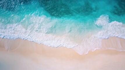 Obraz premium Aerial view of turquoise ocean waves gently washing onto a pristine sandy beach coastline