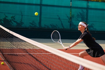 Focused tennis girl at net, ready to hit incoming ball during game.