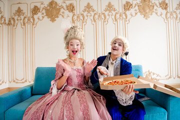 Aristocratic couple in baroque attire enjoy pizza together in a lavish retro-style lounge during a cozy theme party
